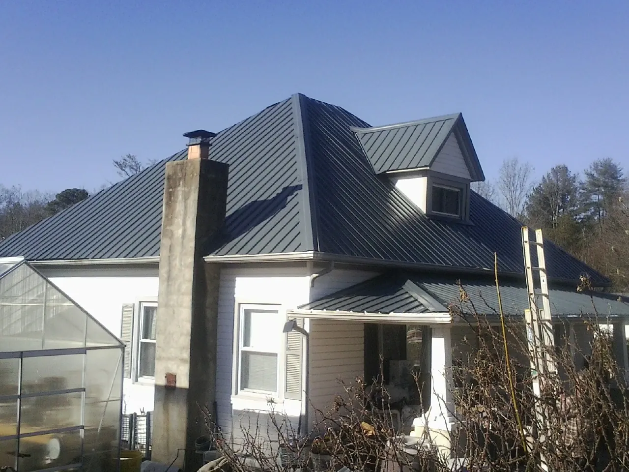 Dark blue standing seam metal roof on a white farmhouse with dormer — Slate & Tile Roof Repair by Roofing Brothers in Sheffield Lake