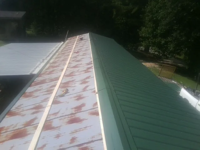 Old rusted panels beside newly installed green metal roofing — Wind Damage Roof Repair by Roofing Brothers in Sheffield Lake