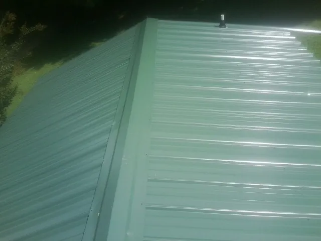 New green metal panels meeting at the ridge of a roof — Flat Roof Repair work by our crew in Sheffield Lake