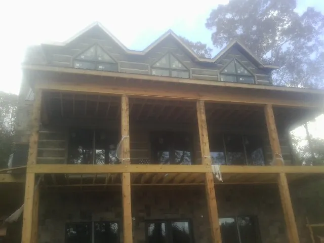 Dormers and porch framing on a large log home under construction — Roof Coating work by our crew in Sheffield Lake