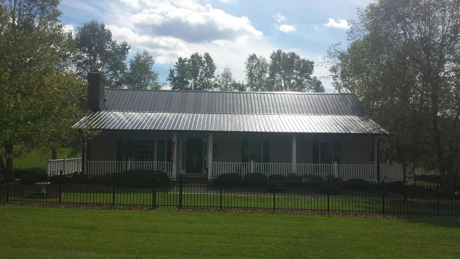 Gray metal roof on a brick ranch with a full width front porch — Gutter Guard Installation work by our crew in Sheffield Lake
