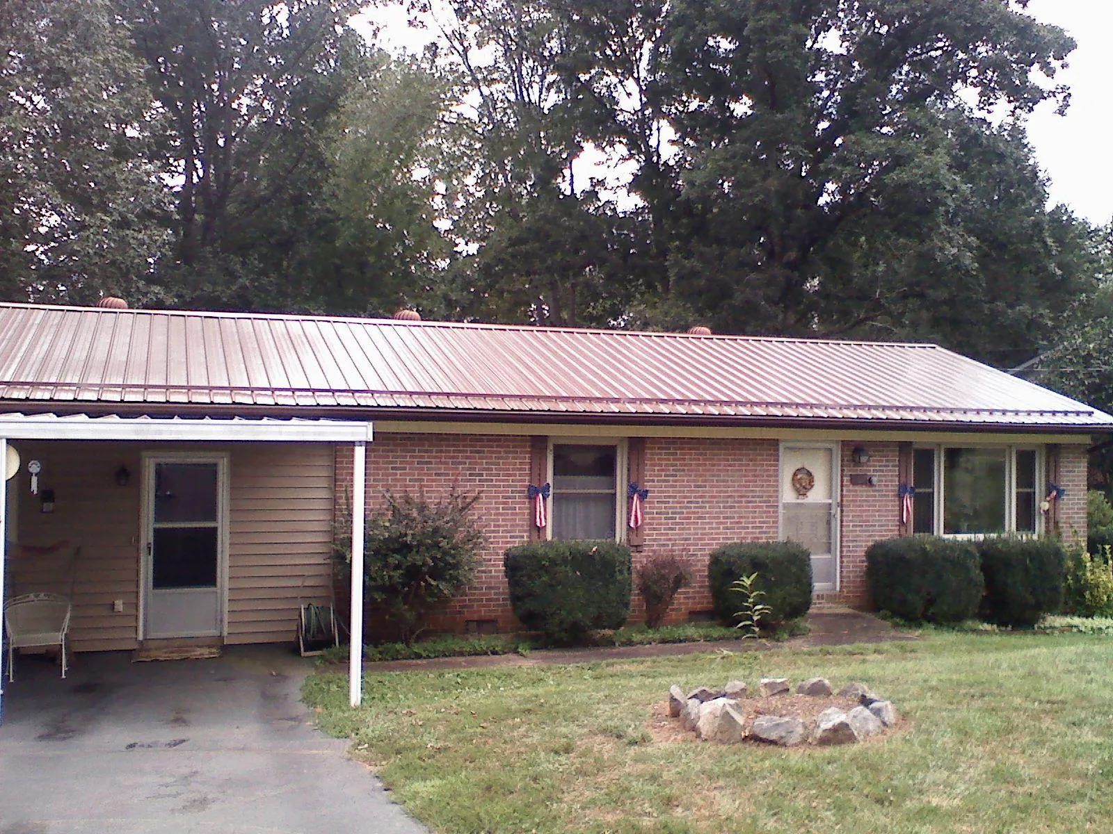 Bronze metal roof and carport on a brick ranch home — Roof Repair work by our crew in Sheffield Lake