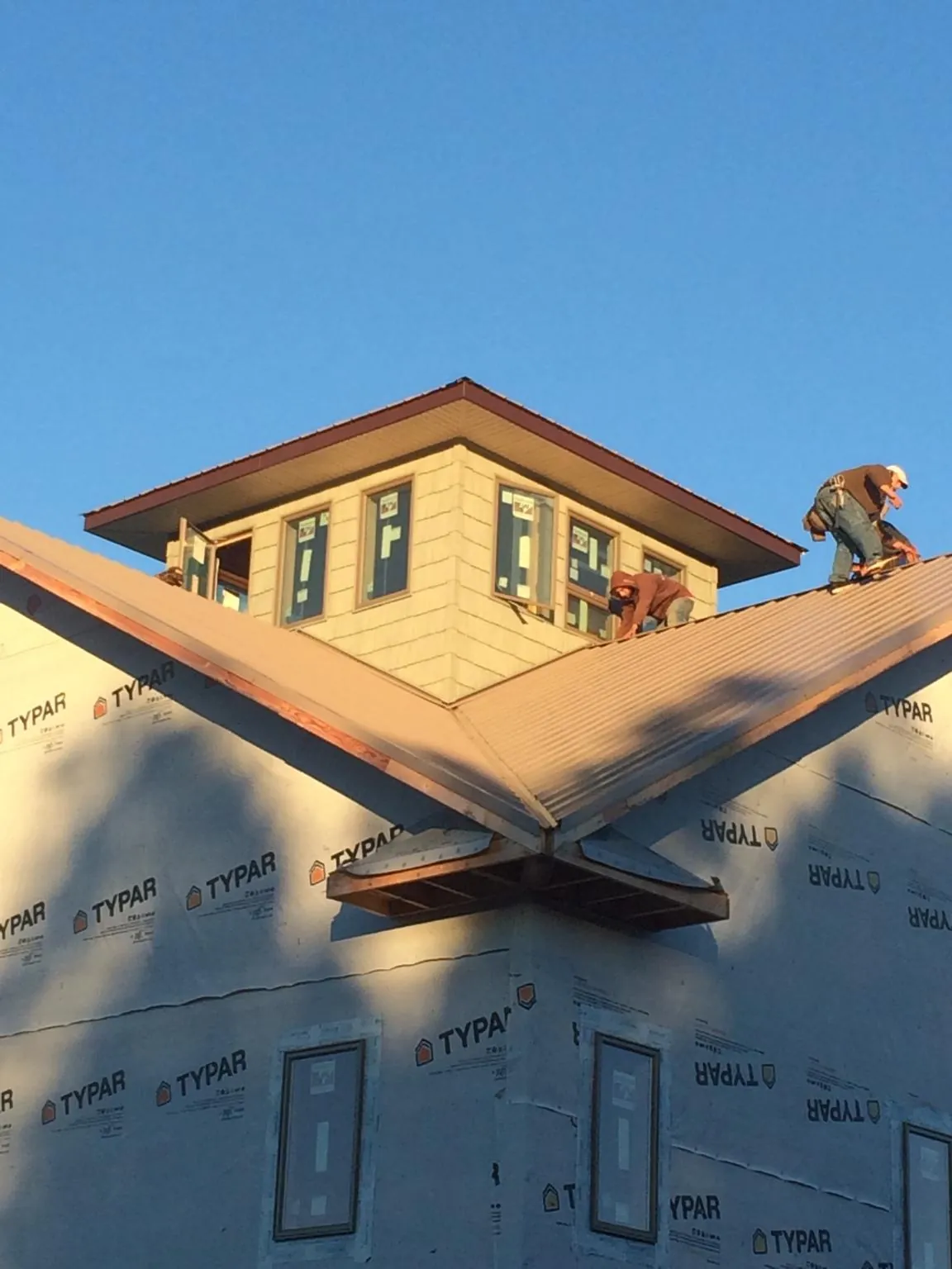 Roofers working around a rooftop cupola on a new metal roof at sunset — Roof Waterproofing in Sheffield Lake by Roofing Brothers